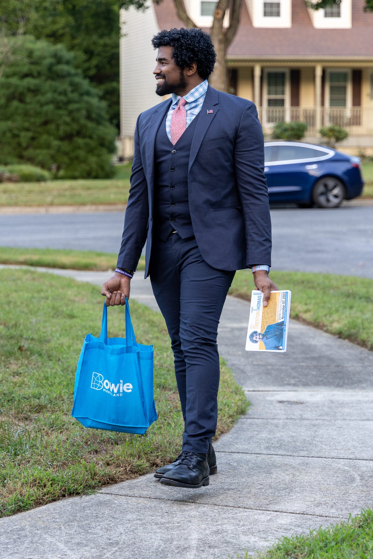 Preston Thomas walking a Bowie sidewalk with campaign literature and a Bowie bag