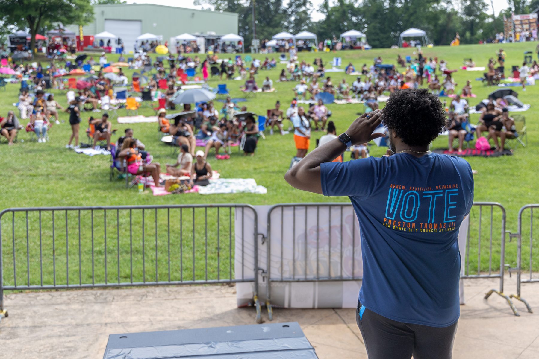Preston Thomas addressing a large outdoor crowd from a stage